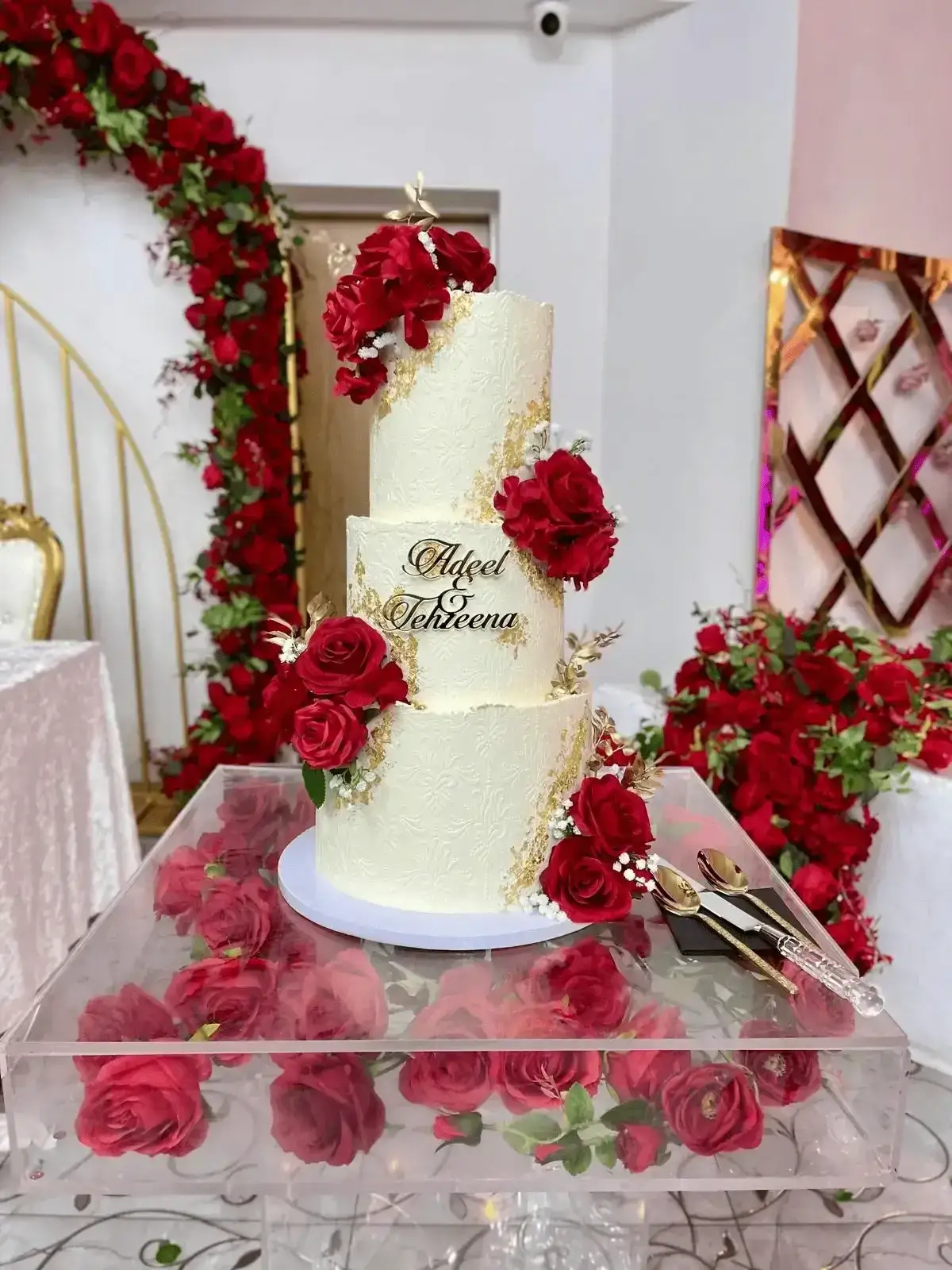 Elegant three-tier wedding cake with red floral decorations