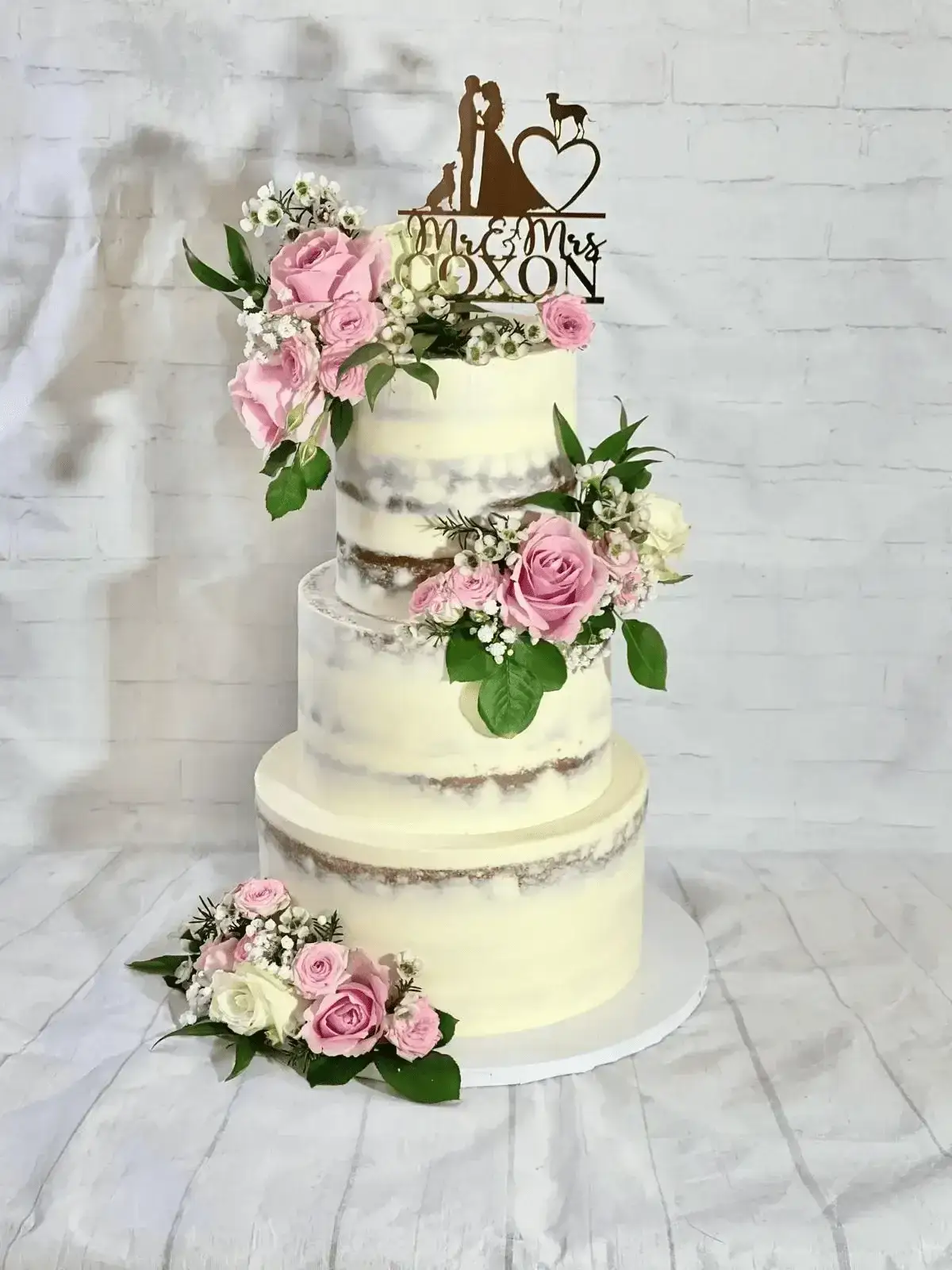 Semi-naked wedding cake with pink roses and topper