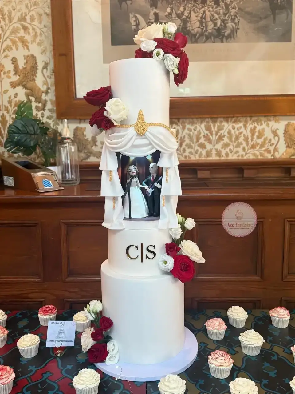 Tall white wedding cake with draped theater scene detail